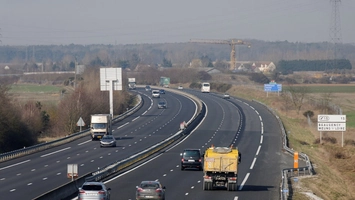 Multi-lane motorway with light traffic and green directional signage visible