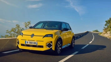 Yellow Renault 5 electric hatchback on a winding road under a blue sky
